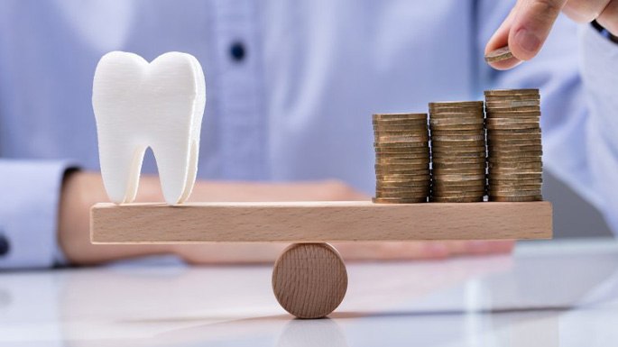 a tooth and a stack of coins on a scale