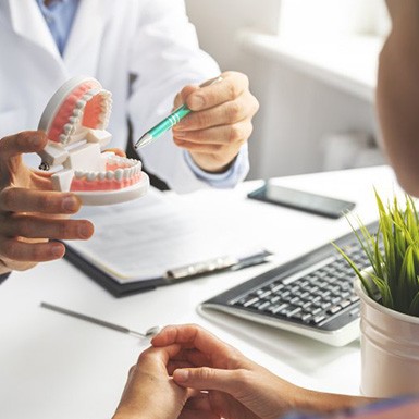 a dentist holding a model of teeth to a patient