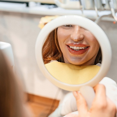POV shot of female patient checking her smile in a handheld mirror