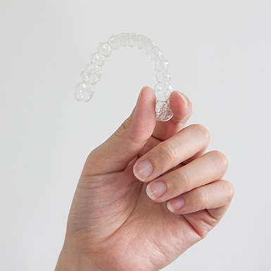 Hand holding an Invisalign clear aligner