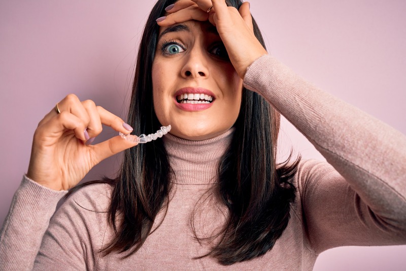 Patient grinding their teeth holding their Invisalign aligner