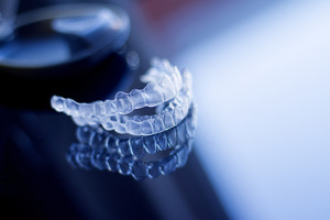 Two Invisalign aligners on a reflective surface