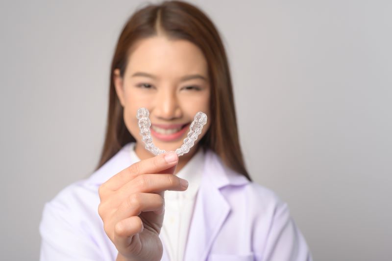 A woman holding an Invisalign aligner